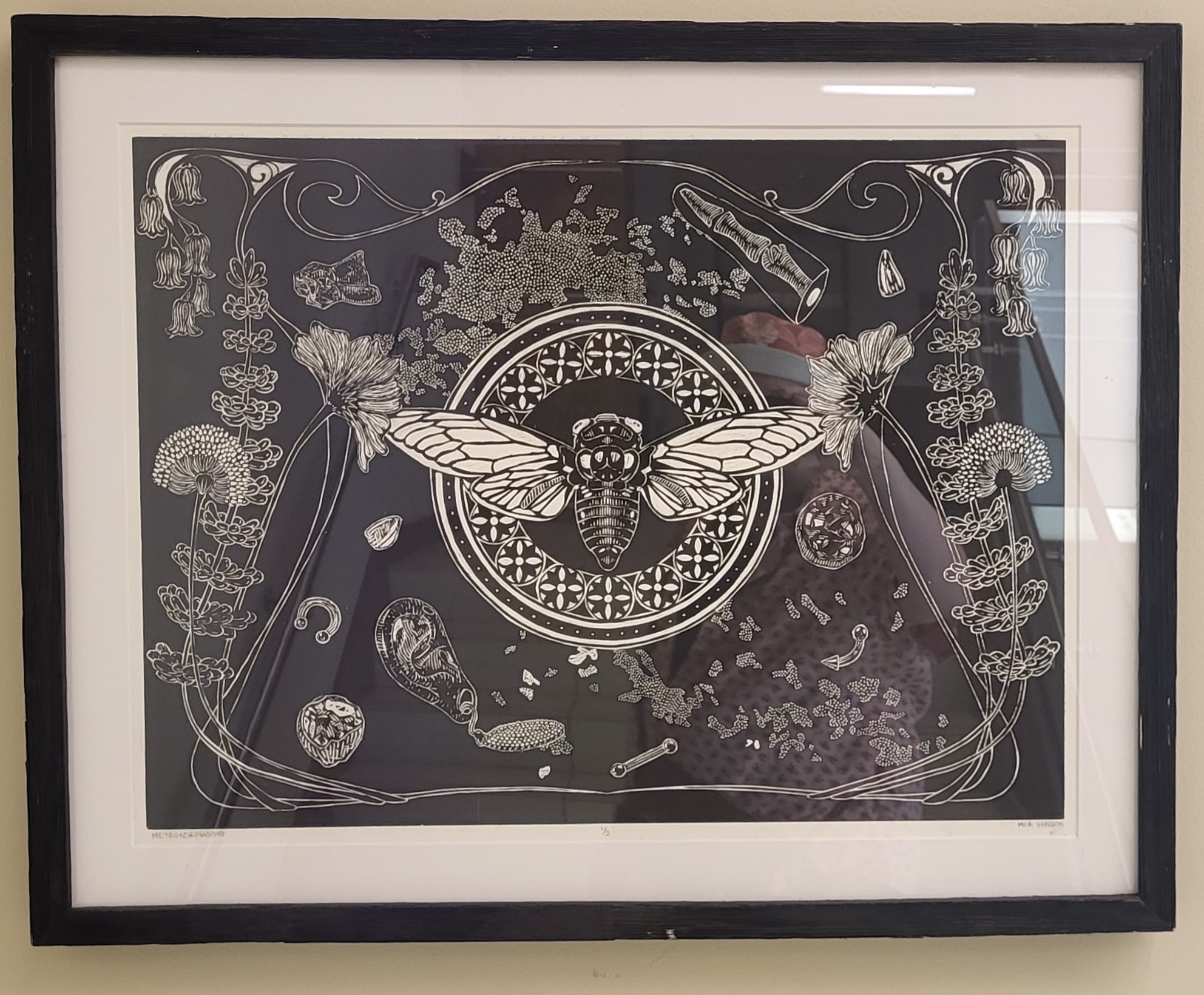 Framed black and white artwork featuring a detailed cicada in the center, surrounded by floral and abstract patterns, evoking a sense of symmetry and nature.