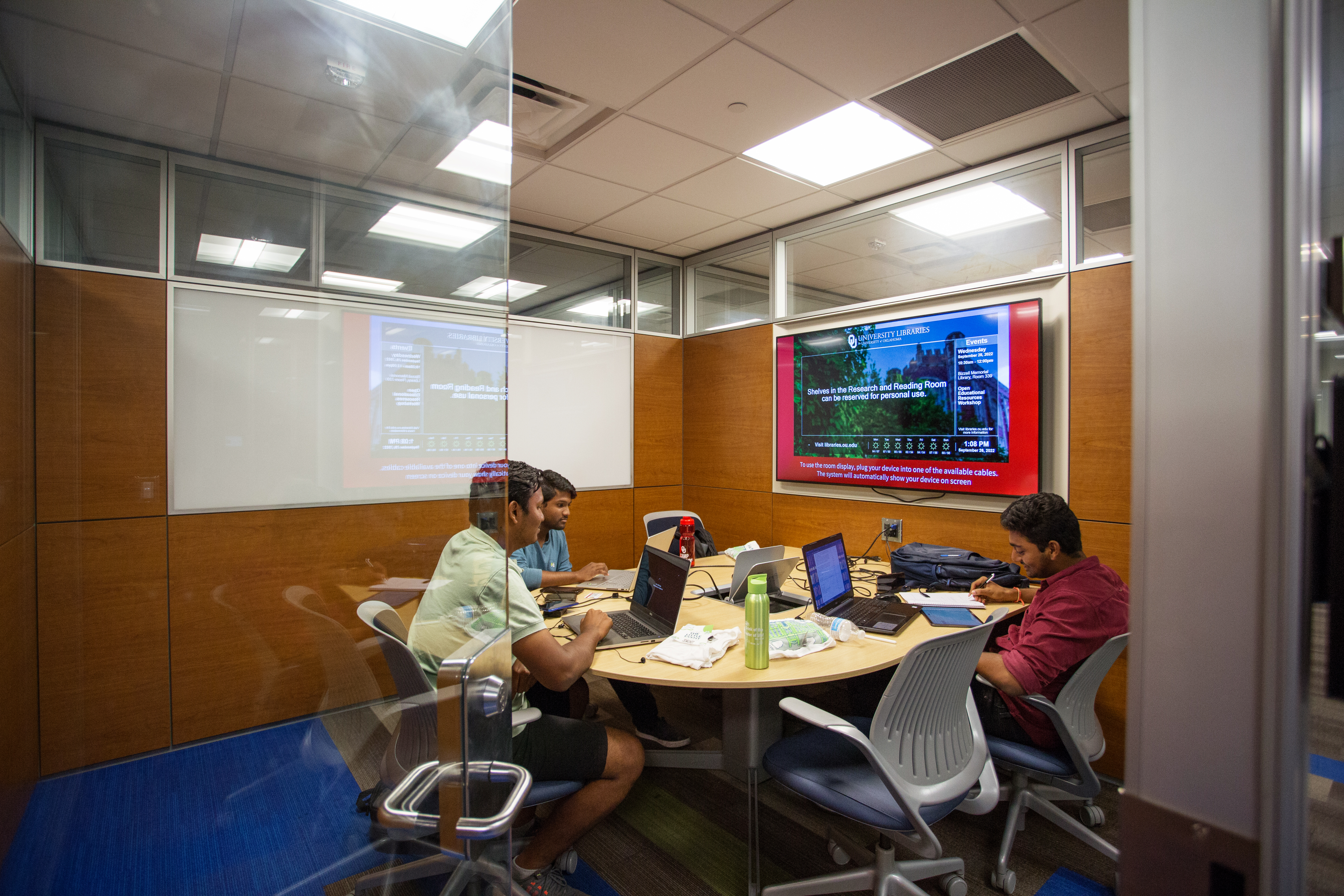 Collaboration room that features a table in front of a display screen with seating for five people. 