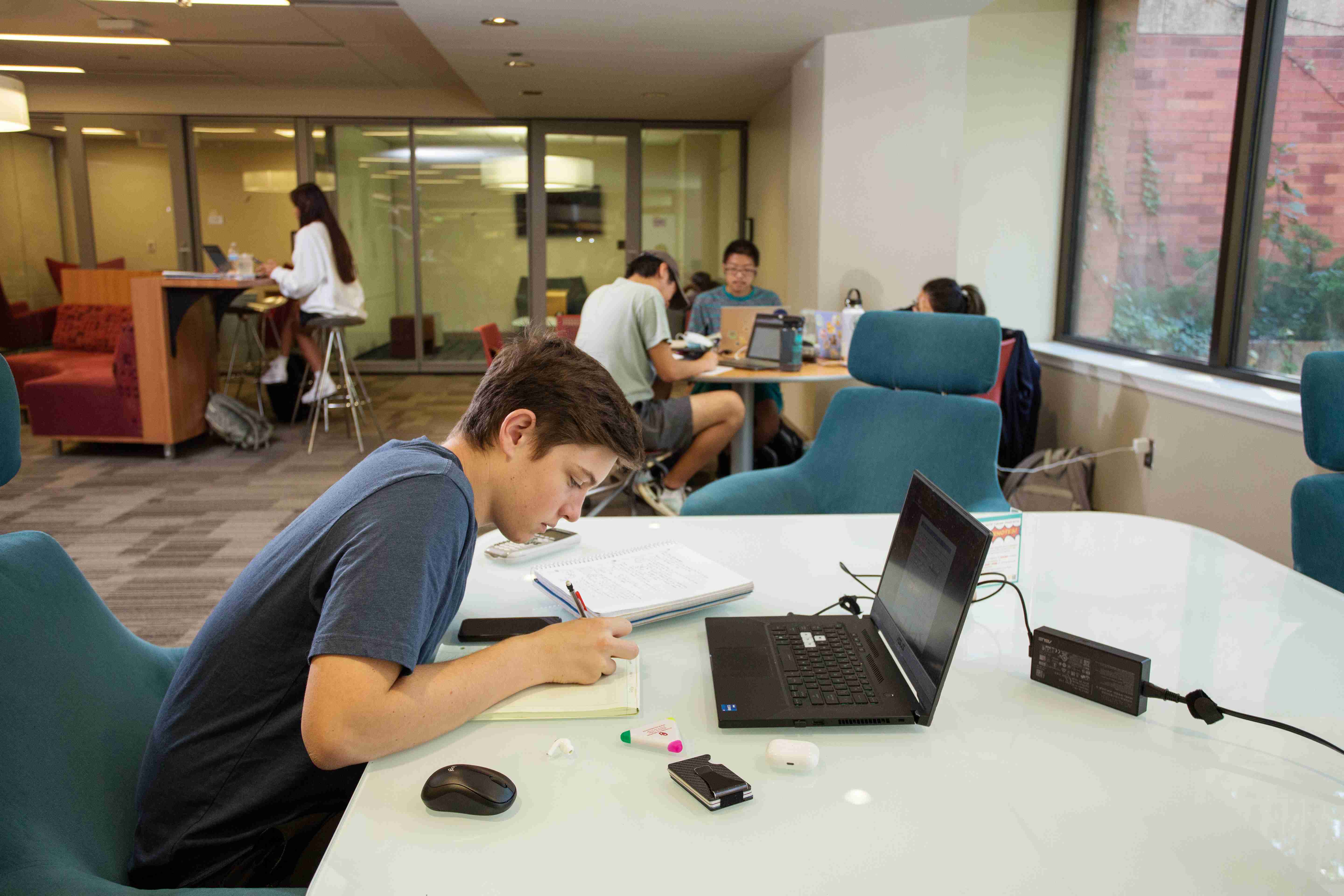 A student is studying at a large table in the open study area on Lower Level 1 of Bizzell. In the background, there are more students studying at other tables.