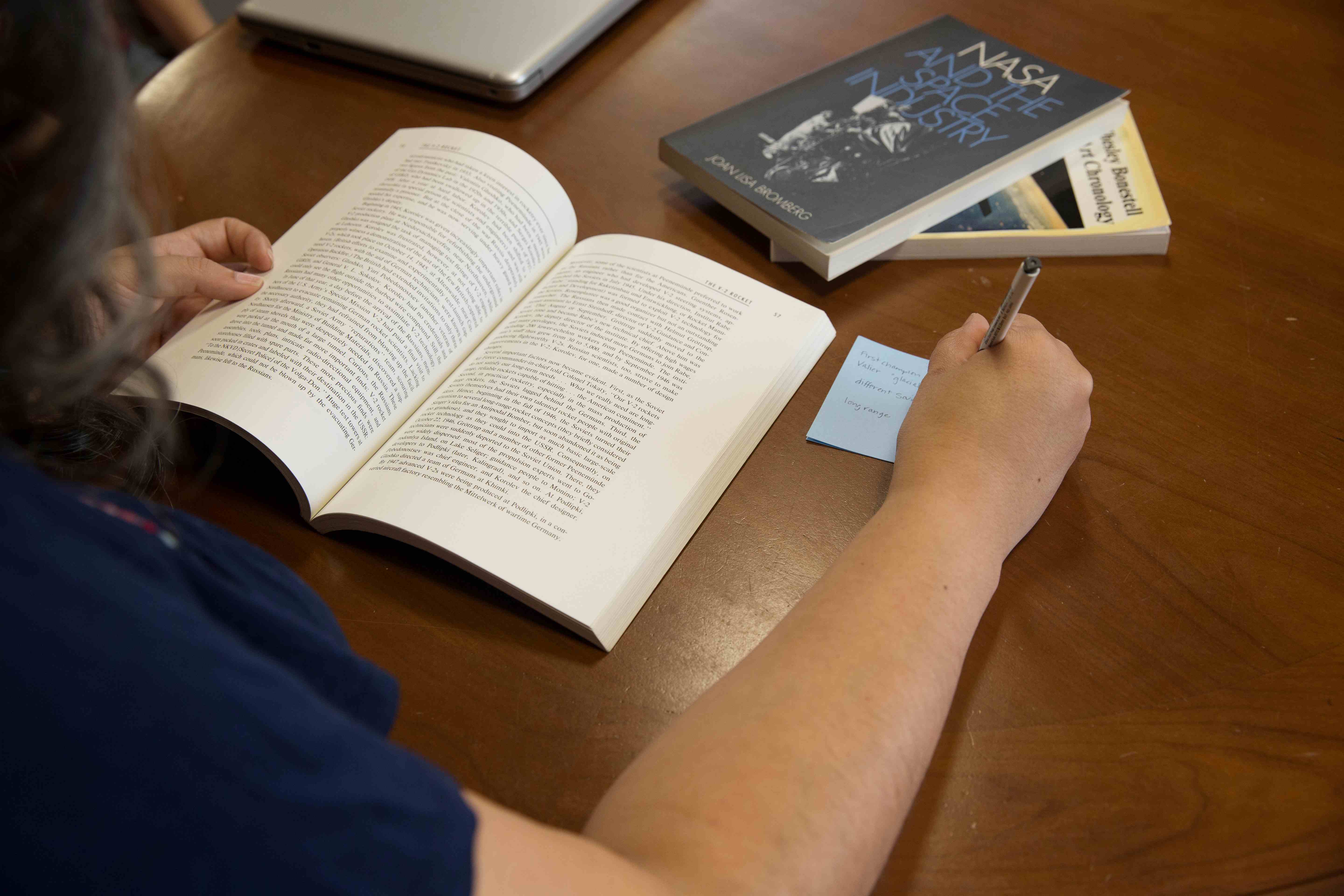 Close up of a person reading a book and making notes 