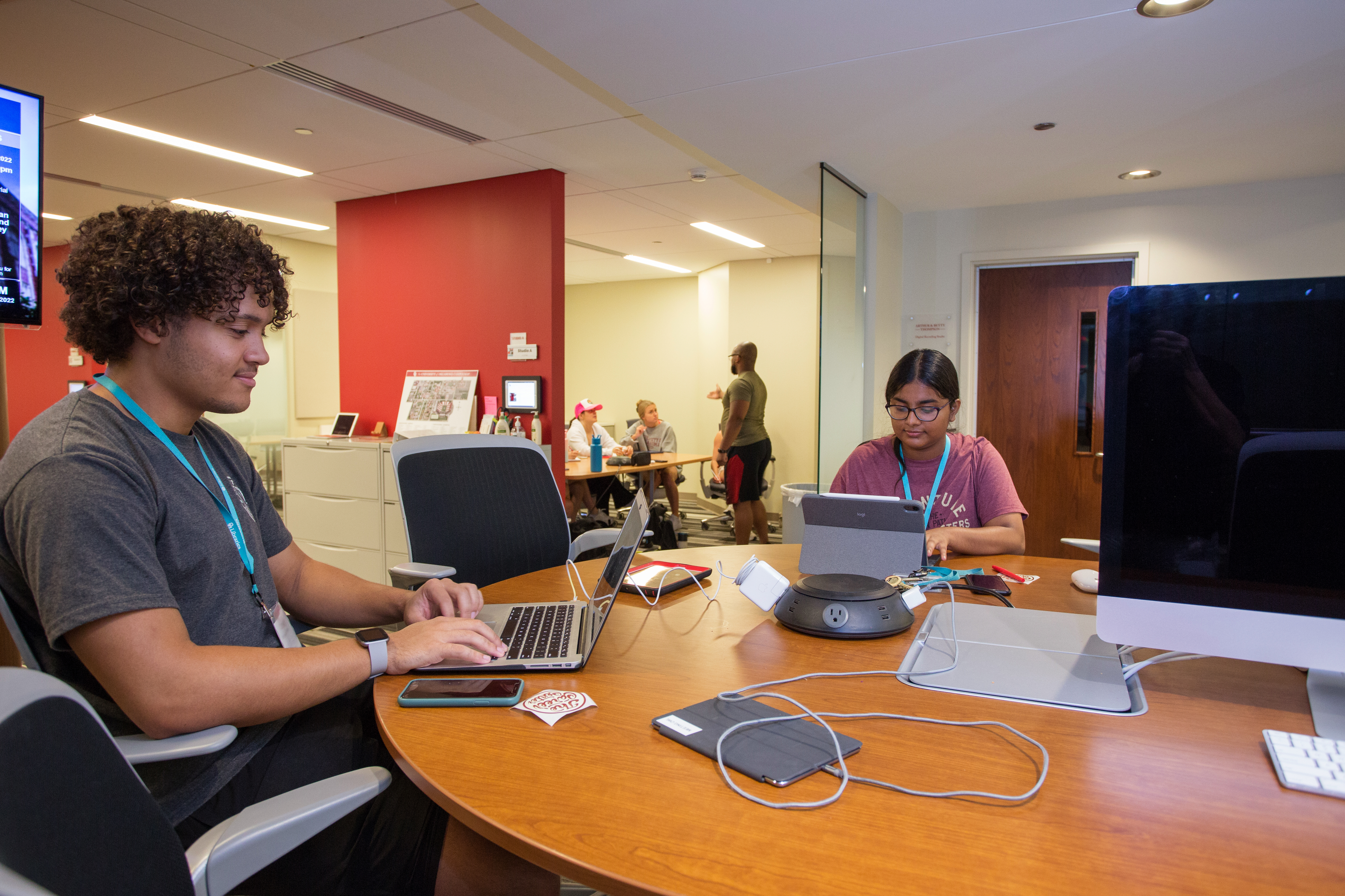 Students work on their laptops at a table in a meeting space
