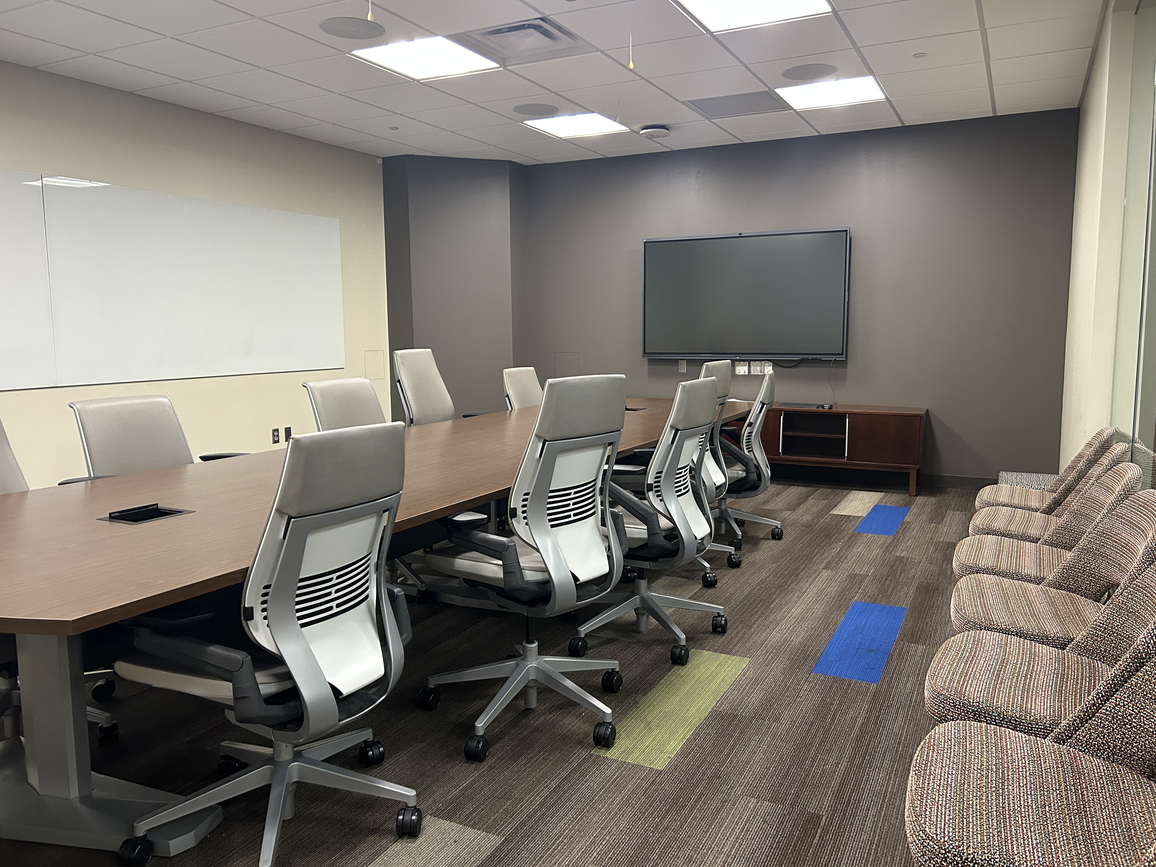 Large conference room with a conference table, several chairs, a whiteboard, and a television screen