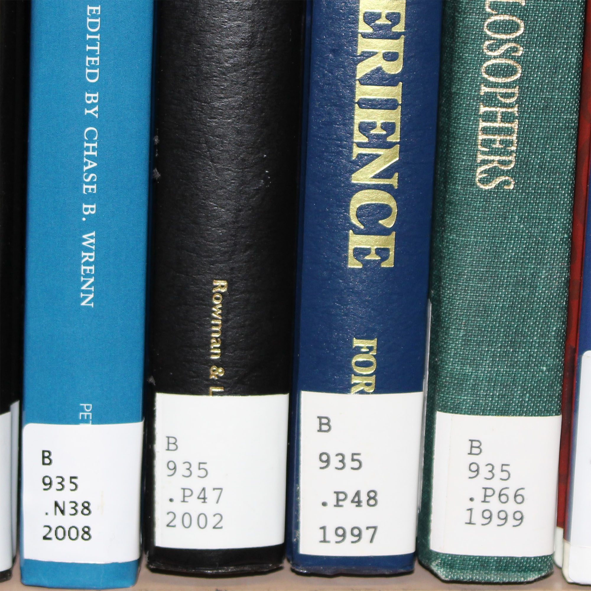 Closeup of four books on a shelf that show the details of their Library of Congress call numbers on the spine of the books.
