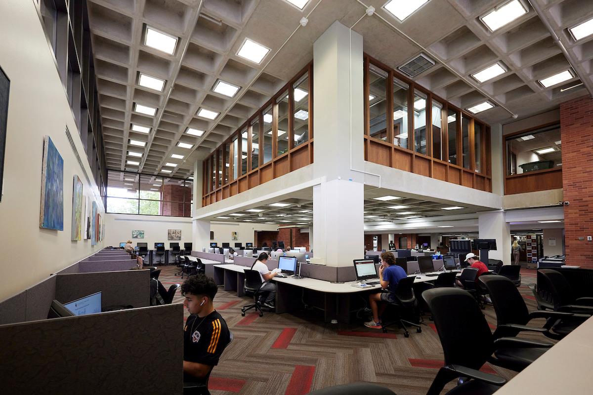 The computer lab in Bizzell. There are rows of desks along three walls, making a giant U-shape, then additional desks in the middle. There are a handful of people using the computers in the area. 