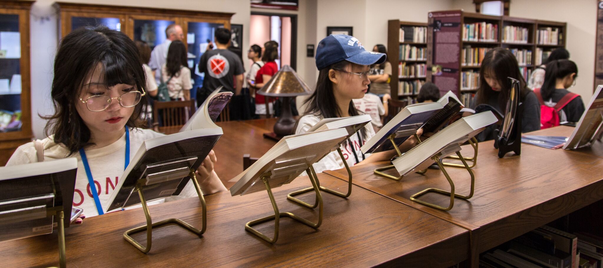 Students are viewing books that are on small display stands in the Chinese Literature Translation Archive room