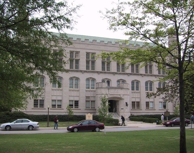 A view of the front of Monnet Hall. It's a 3-story white stone building with a green roof. 