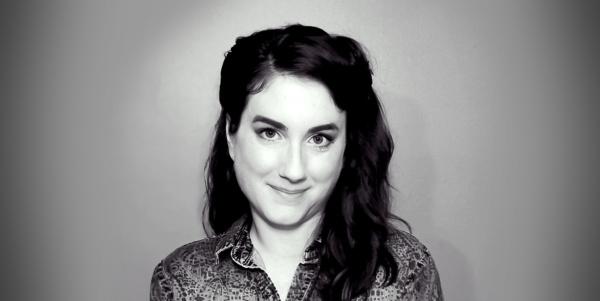 Black and white headshot of Colleen Cressman. She has dark, wavy hair, is wearing a patterned blouse, and smiles softly at the camera.